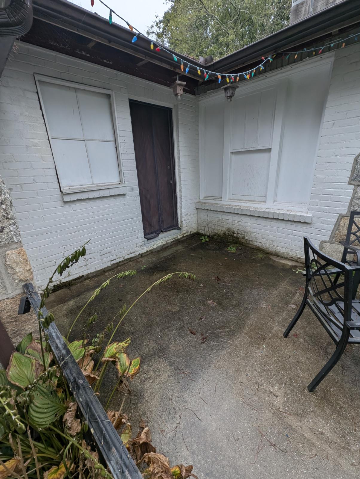 White painted brick patio, brown door, string lights.